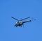 A helicopter of agricultural aviation is flying in the blue sky.