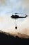 A helicopter carrying water to put out a wildfire.