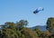 Helicopter is flying in the blue sky over the trees. Agricultural work. Transportation aircraft. Spraying fields