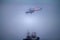 Helicopter performs loading operations on icebreake in fog