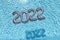 Helium balloons with numbers 2022 lying on water in swimming pool top view closeup background