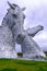 Helix Park, Scotland, 2018 - two people walk under The Kelpies large horse sculptures by Andy Scott, an example of public art