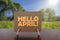 Hello April text on card on the table with sunny green park background