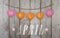 Hello April written on hanging pink and orange hearts and weathered wooden background