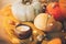 Hello autumn. Cozy rustic moody image. Pumpkins, autumn leaves, candle, warm lights and acorns, walnuts, berries on yellow knitted