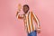 Hello! Cheerful friendly afro-american man with dreadlocks in bright striped shirt and denim pants saying hi and waving hand,