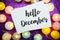 Hello December text on paper card top view on purple bokeh background