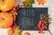 Hello fall. Pumpkins, berries and fallen leaves with chalk blackboard frame on wooden background. Halloween