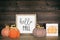 Hello fall sign with rustic pumpkin home decor on a shelf against dark wood