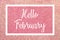 Hello February greeting card with white text over a pink glitter background