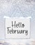 Hello February text on white plate board banner with cold snow f