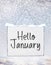 Hello January text on white plate board banner with cold snow fl