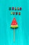 Hello June text from colorful letters and watermelon lollipop on stick on wooden blue background. Concept Creative Top