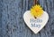 Hello May greeting card with decorative white heart and dandelion yellow flower on old blue wooden background.