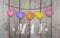 Hello May written on hanging pink and orange and purple hearts and weathered wooden background