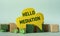 HELLO MEDIATION - words on yellow paper against a background of scattered wooden cubes on a mint background