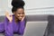 Hello nice meet you. Happy Afro-American woman with afro hairstyle lying on couch, waving hi greeting gesture, looking at camera