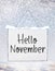 Hello November text on white plate board banner with cold snow f