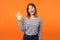 Hello! Portrait of adorable friendly woman with brown hair in long sleeve striped shirt. indoor studio shot isolated on orange