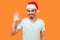 Hello! Portrait of positive handsome bearded man in santa hat and casual white t-shirt waving raised hand and saying hi to camera