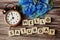 Hello Saturday alphabet letters with alarm clock and blue flower on wooden background