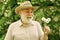 Hello summer. senior man blowing dandelion seeds in park. elderly man in straw summer hat. Concept memory loss. concept