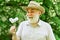 Hello summer. senior man blowing dandelion seeds in park. elderly man in straw summer hat. Concept memory loss. concept