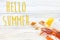 hello summer text, vacation concept. colorful towel, sunglasses, yellow sunscreen and star shells on white rustic wooden