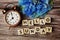 Hello Sunday alphabet letters with alarm clock and blue flower on wooden background