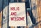 Hello and welcome symbol. Conceptual words hello and welcome on notepad and vintage background