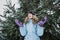 Hello winter, happy wintertime. Happy young curly woman with hands raised up celebrating winter snow standing in snowy