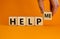 Help me symbol. Businessman holds wooden cubes with words help me. Beautiful orange background, copy space. Business, motivational