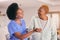 Help, nurse and holding hands of senior black woman, care and smile in house together. Caregiver, support and elderly