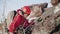 With the help of a strong rope, a young climber descends down a steep stone slope