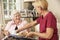 Helper Serving Senior Woman With Meal In Care Home