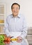 Helpful man preparing salad in kitchen