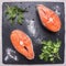 Helpful sports foods, cooking two fresh salmon steak with herbs and spices,on cutting board stone, top view close up
