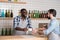 Helpful young waiter giving his colleague a cup and smiling cheerfully