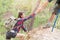 Helping hand - hiker woman getting help on hike smiling happy overcoming obstacle. Tourist walking on the Mountain, Young couple