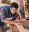 It helps to be precise. a focused handyman measuring a piece of wood while working in his workshop.