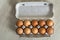 Hen eggs in open cardboard egg carton on kitchen table light copy space background. Healthy organic food and diet concept