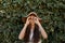 Her beauty is so natural. a pretty teenage girl standing in front of a large hedge.