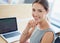 Her career is trending. Portrait of a smiling young businesswoman sitting at a table in an office using a laptop.