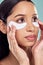 Her eyes are full of stories. a young woman using eye masks against a studio background.