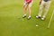 Her first shot found the green. two unrcognizable people playing golf together.