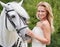 Her most trusted steed will spirit her to the aisle. Portrait of a gorgeous blonde bride standing alongside her stallion