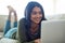 Her social media feeds are buzzing. Shot of an attractive young woman using her laptop while lying on the sofa at home.