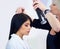 Her stylist has the golden touch. A young model at the salon having hairspray applied to her hair.