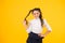 Her twisted hairdo. Small girl winding long hairdoaround her finger on yellow background. Little kid with ponytail