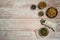 Herbal decoction of calendula and various dried herbs in linen bags and cups on a light wooden background.